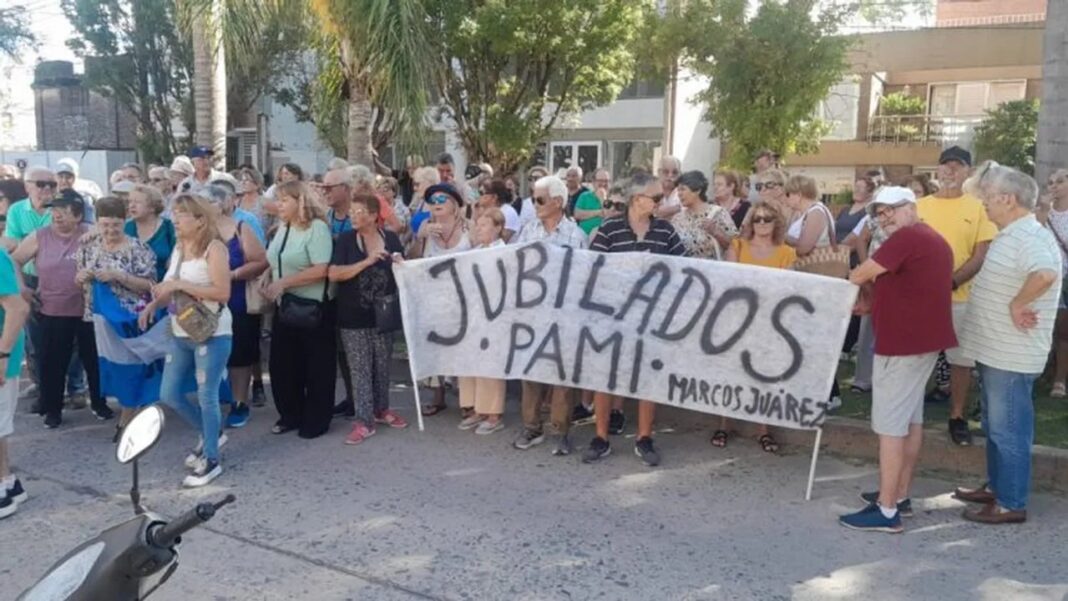 Personas mayores y vecinos reunidos frente a un edificio en Marcos Juárez, Córdoba.